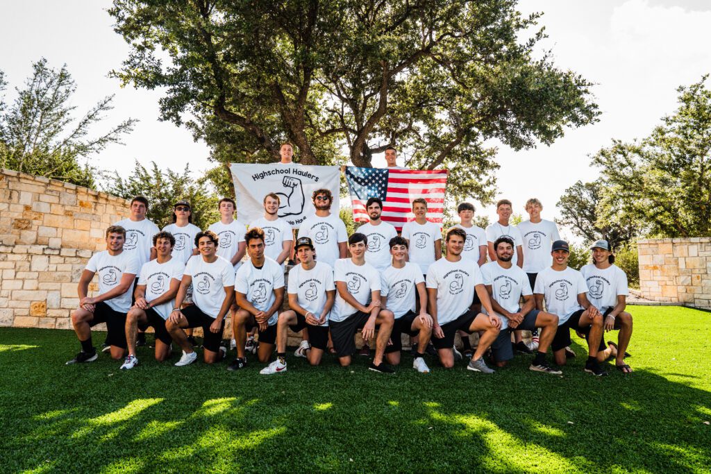 The Highschool Haulers crew in matching white shirts with an American flag and a company banner
